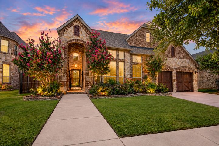 Stone and brick two-story front exterior of 4009 Jasmine Fox Lane at twilight, with a lit arched entry